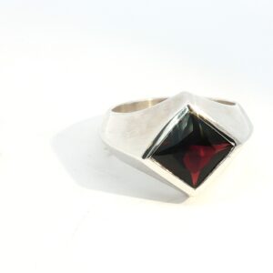 Make a bold statement with the Square-Cut Garnet Signet Ring in Sterling Silver, a timeless piece crafted for both men and women. This striking unisex ring features a deep red garnet gemstone cut in a sleek square profile and set in a polished sterling silver band. Its clean lines and modern design give it a powerful yet sophisticated look, perfect for everyday wear or special occasions. Garnet is known as a stone of passion and strength, making this ring a meaningful gift or a unique addition to your personal collection. Durable and versatile, it effortlessly blends classic elegance with contemporary edge.