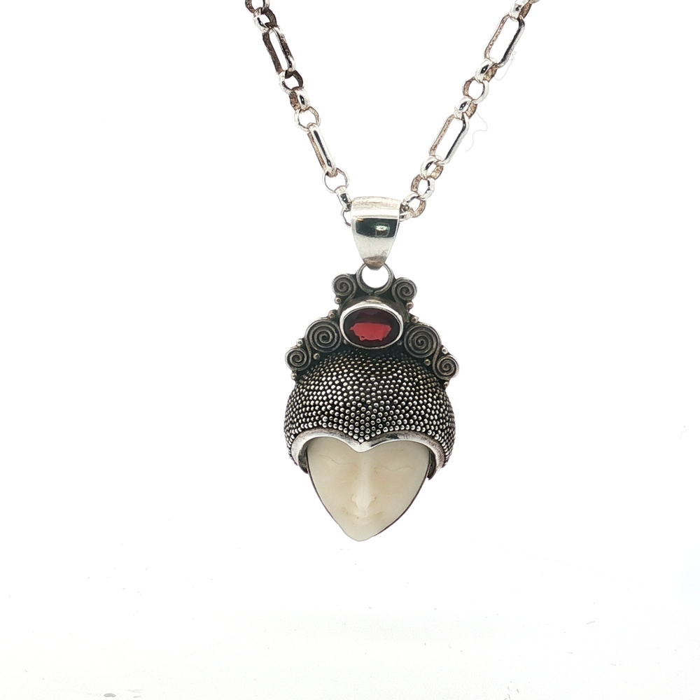 Embrace power, mystery, and timeless artistry with this extraordinary Natural Stone “Little Warrior” Pendant — a handmade masterpiece blending raw gemstone beauty with tribal-inspired design. The pendant features a carved gemstone face cradled in a richly textured sterling silver headdress, crowned with a vivid natural garnet gemstone. The result: a bold, wearable talisman that draws attention, sparks conversations, and captures character wherever you go.